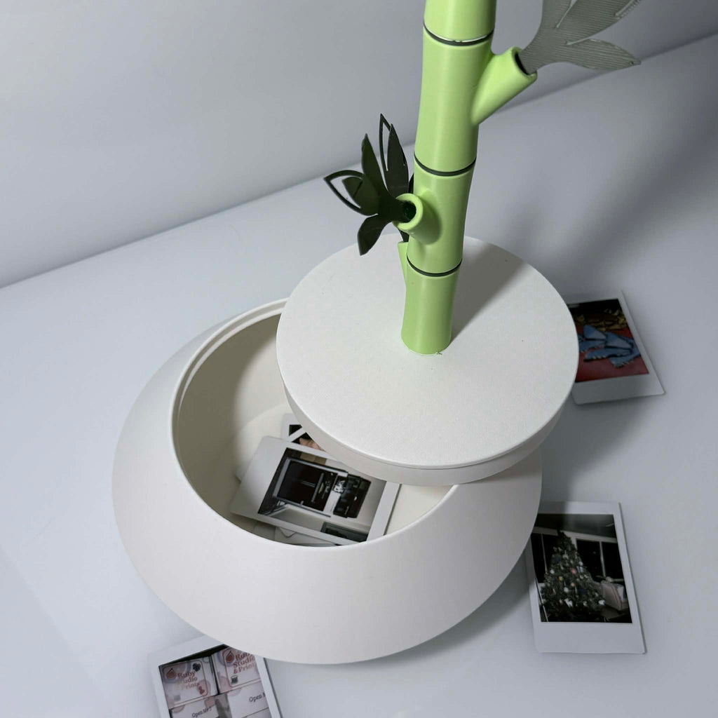 bamboo shoot polaroid holder with pictures scattered and inside the white vase