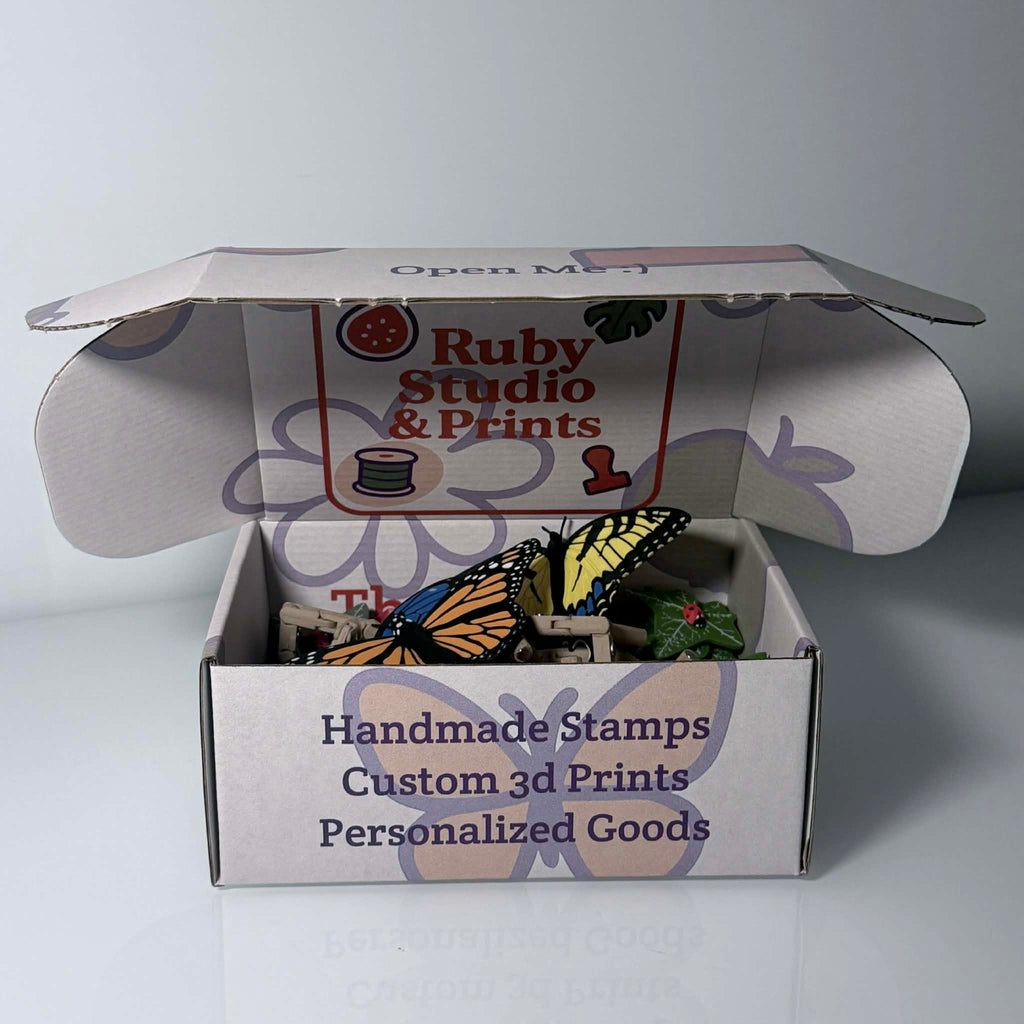 Branded box halfway opened with colorful butterflies, leaves, and ladybug magnets inside
