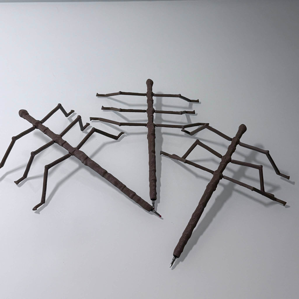 three brown stick bug pens