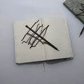 brown stick bug pen on top of an open face blank notebook